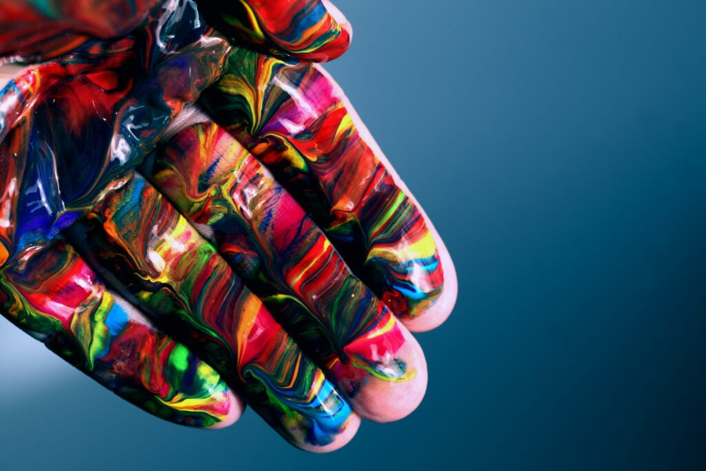 mão pintada com as cores das diferentes orientações sexuais para aludir ao tema da expressão de género e orientação sexual