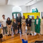 Várias pessoas numa sala posam em frente a um cartaz Pombal + Igual