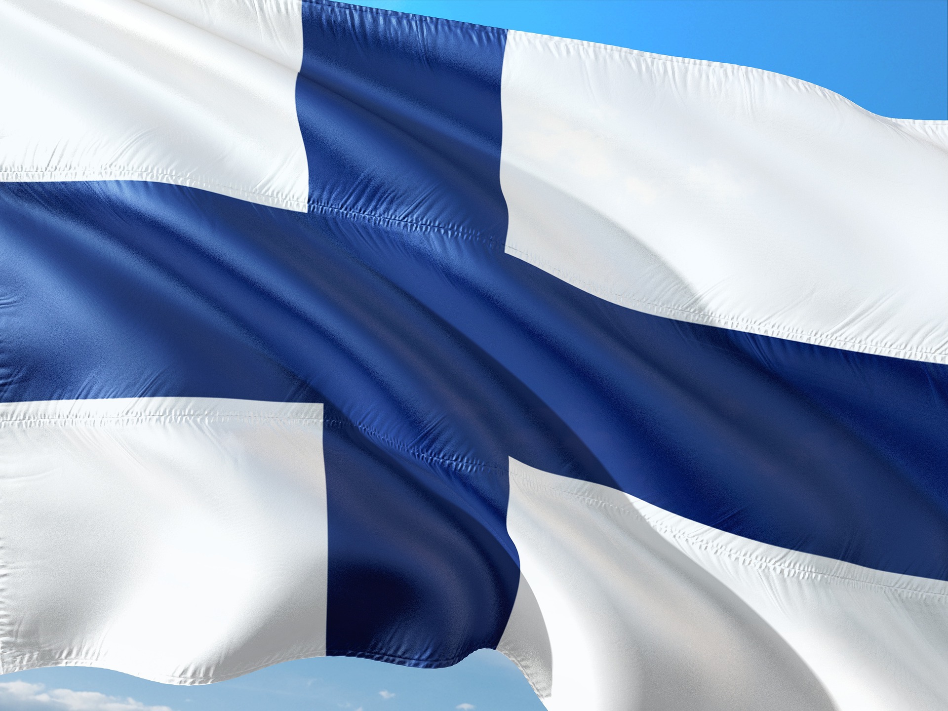 bandeira da finlandia (cruz azul sobre fundo branco)esvoaça sobre um céu azul
