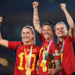 Três jogadoras espanholas a exibir o troféu de campeãs do mundo