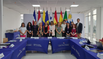 homens e mulheres posam de pé em frente a bandeiras de diversos países