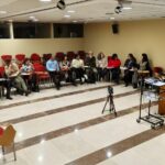 Fotografia do grupo de trabalho dispoto em formato de meia de lua