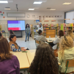 plateia de mulheres sentadas assiste a formação. isabel rosinha e isabel cruz, de pé junto a um ecrã, falam para a plateia