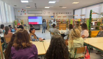 plateia de mulheres sentadas assiste a formação. isabel rosinha e isabel cruz, de pé junto a um ecrã, falam para a plateia